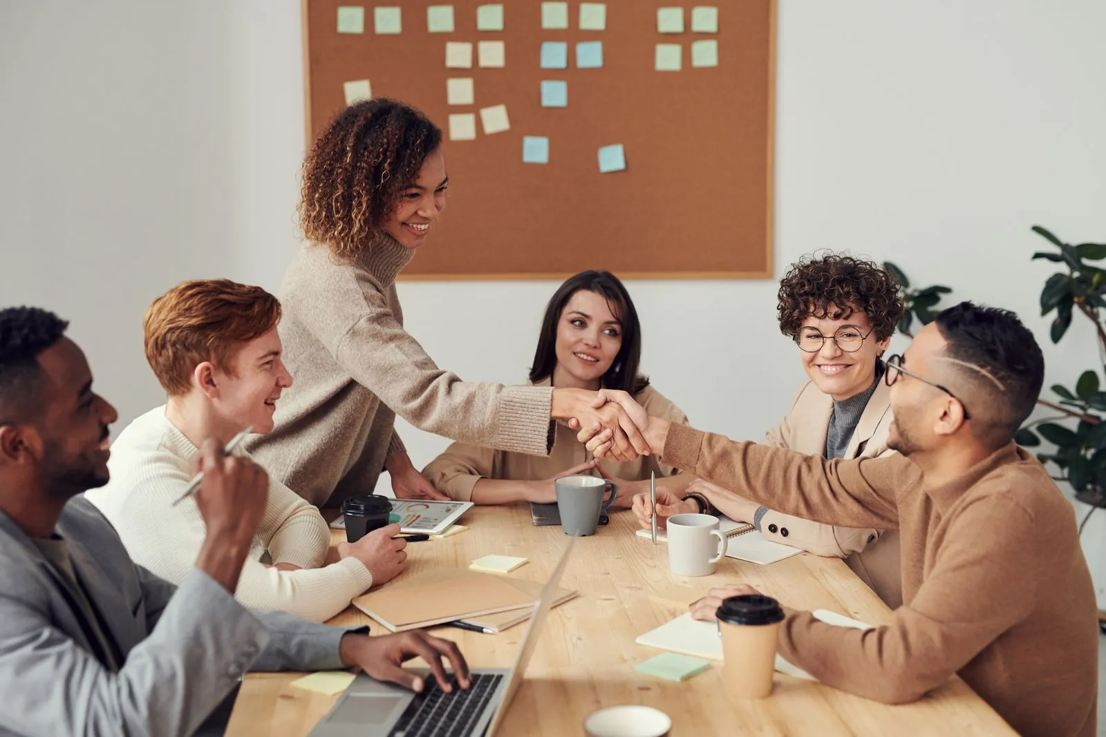 Equipo de trabajo colaborando alrededor de una mesa con laptops